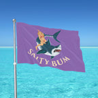 Flag with a shark and bikini-clad figure design against a blue ocean background