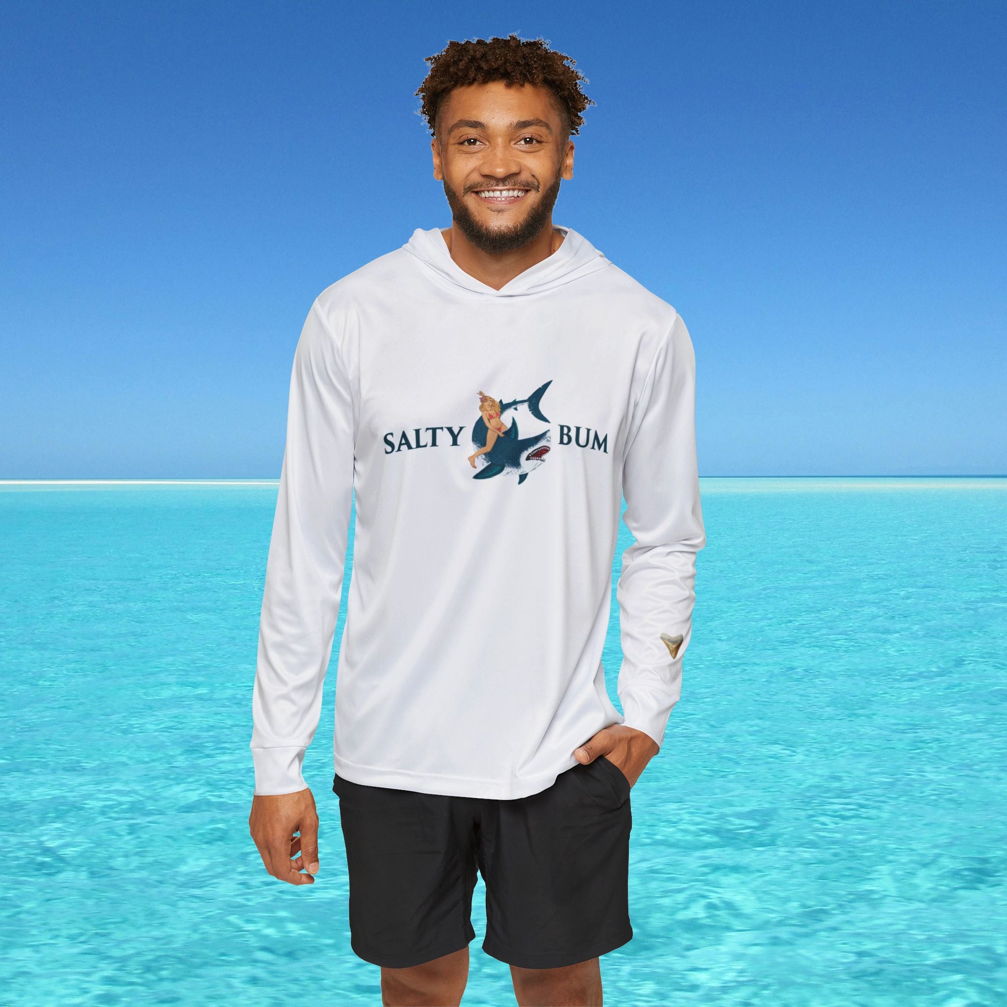 Man wearing a 'Salty Bum' hoodie standing in front of clear blue water.