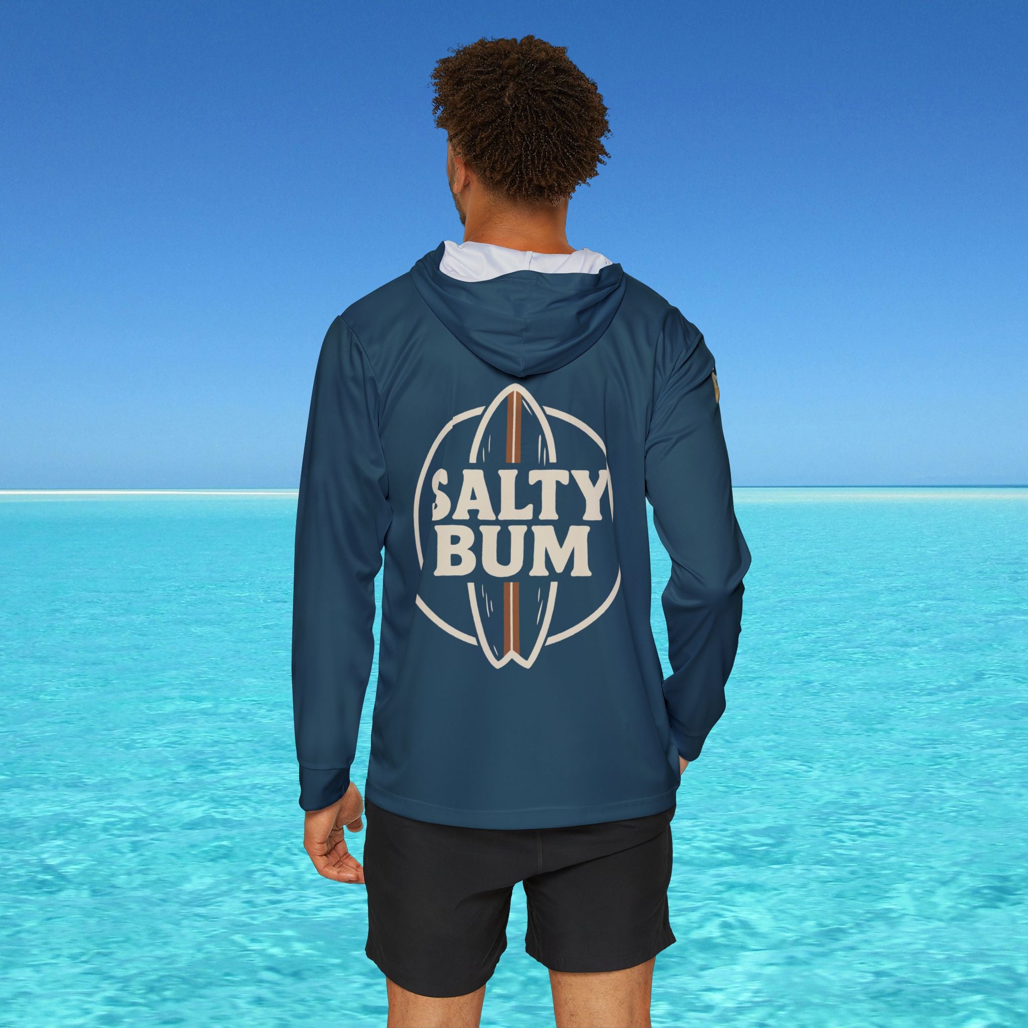 Person wearing a blue hoodie with 'Salty Bum' logo in a tropical setting