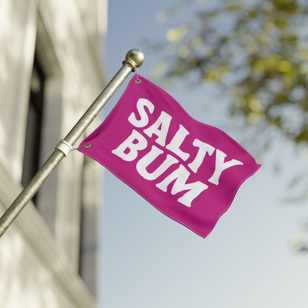 Pink flag with 'Salty Bum' text on a pole against a blurred background
