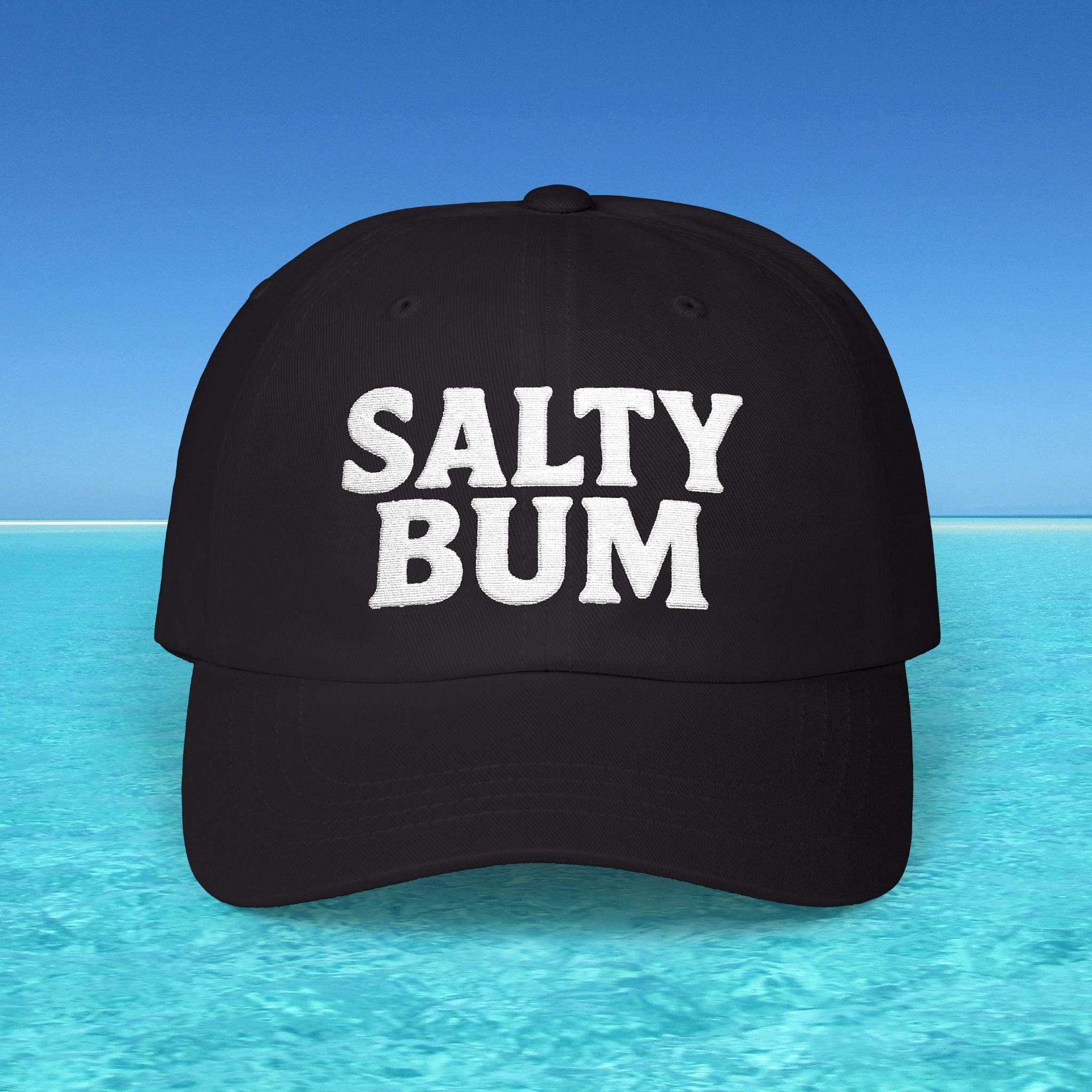 Black cap with 'Salty Bum' text on a blue water and sky background