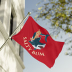 Red flag with 'Salty Bum' design featuring a shark and a woman, against a blurred outdoor background.