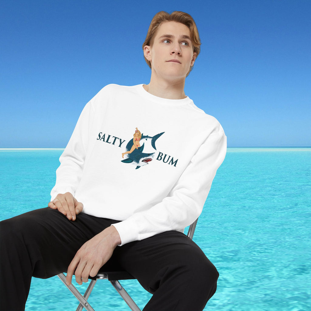 Person wearing a 'Salty Bum' sweatshirt sitting on a chair with a blue ocean background