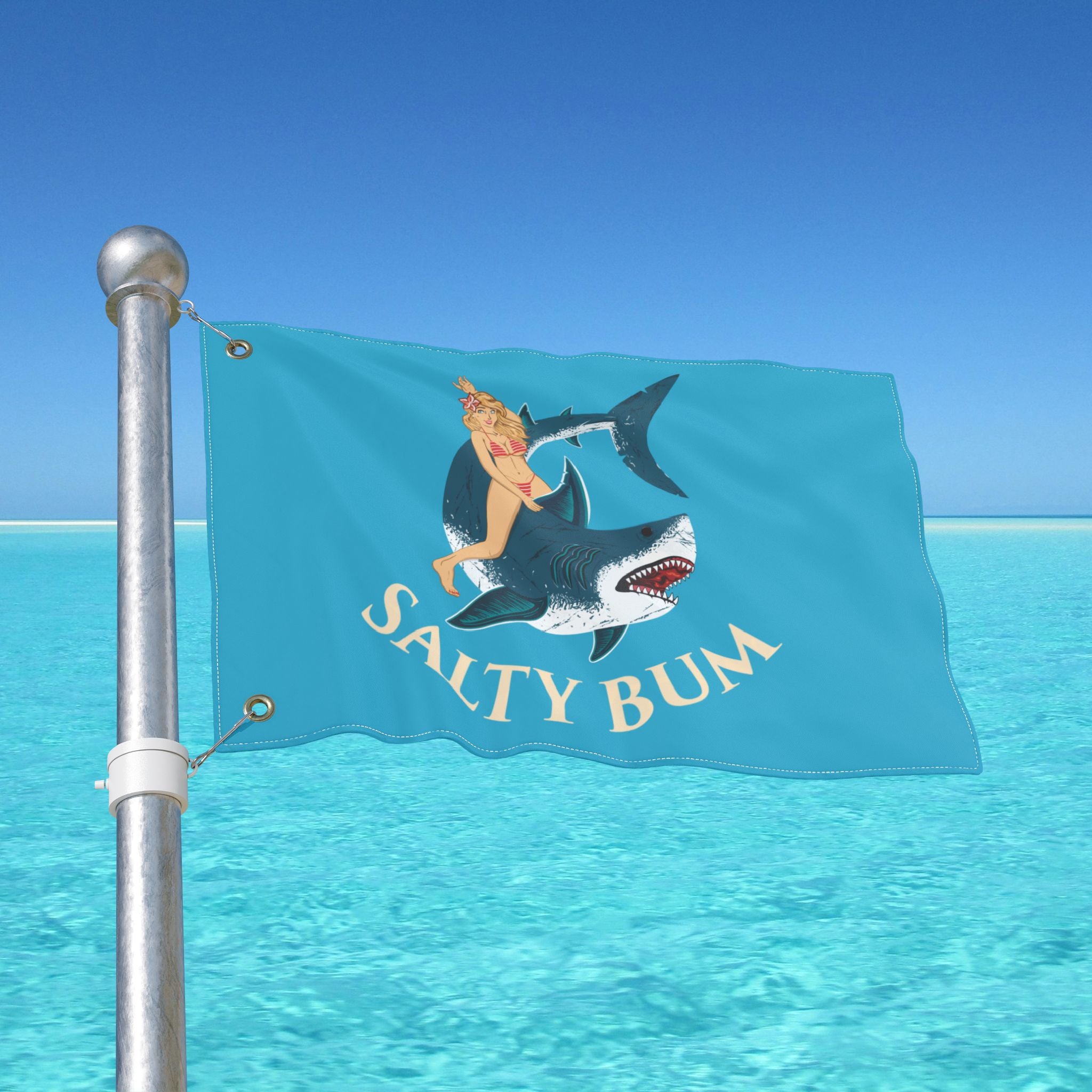 Flag with a shark and person design on a pole against a blue sky and water background