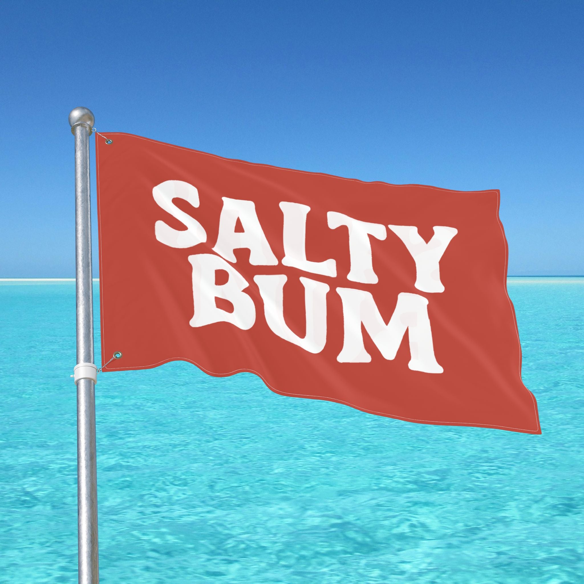 Red flag with 'Salty Bum' text against a clear blue sky and ocean.