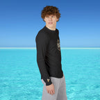 Person wearing a black long-sleeve shirt with a logo standing in front of clear blue water and sky.