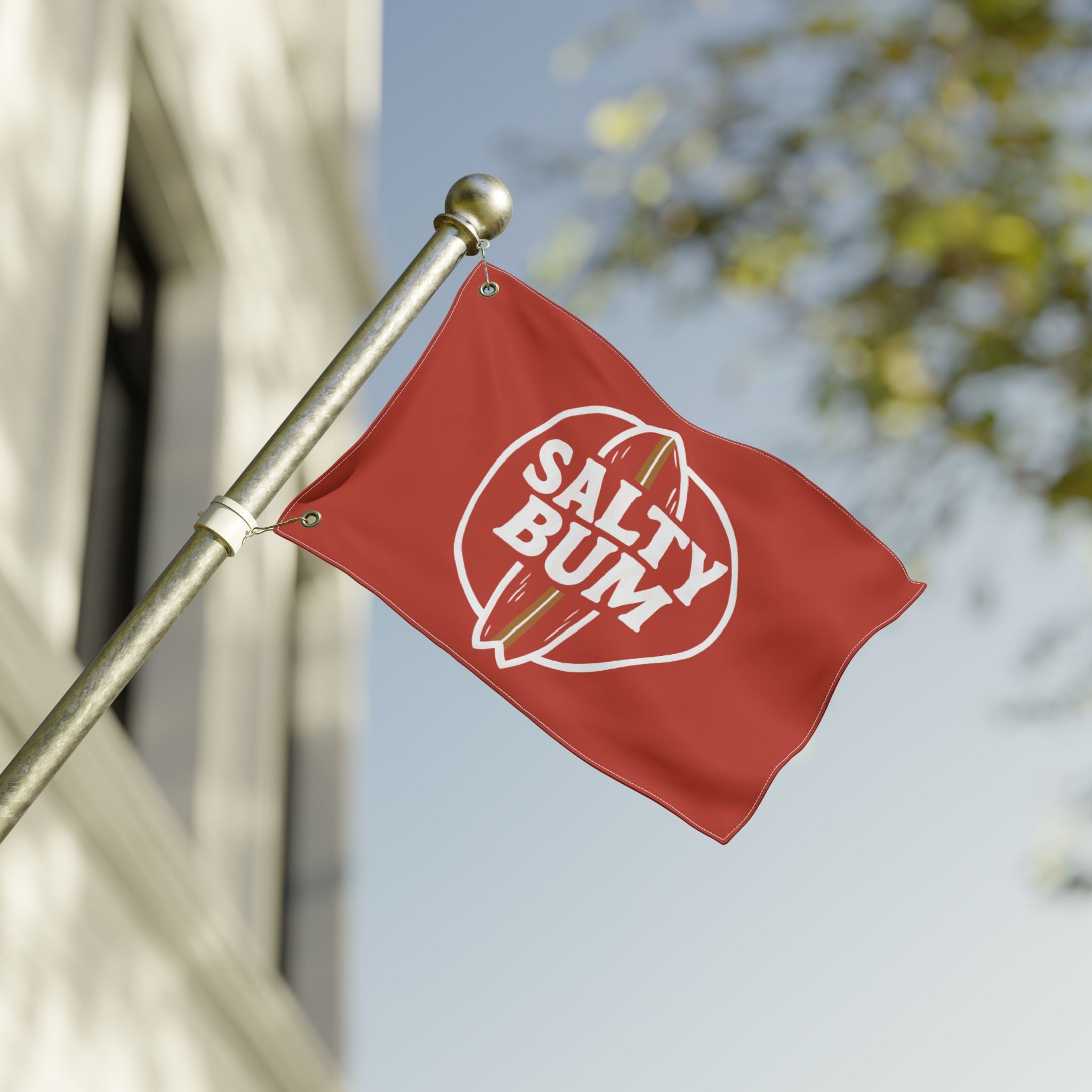 Red flag with 'Salty Bum' logo on a pole against a blurred background