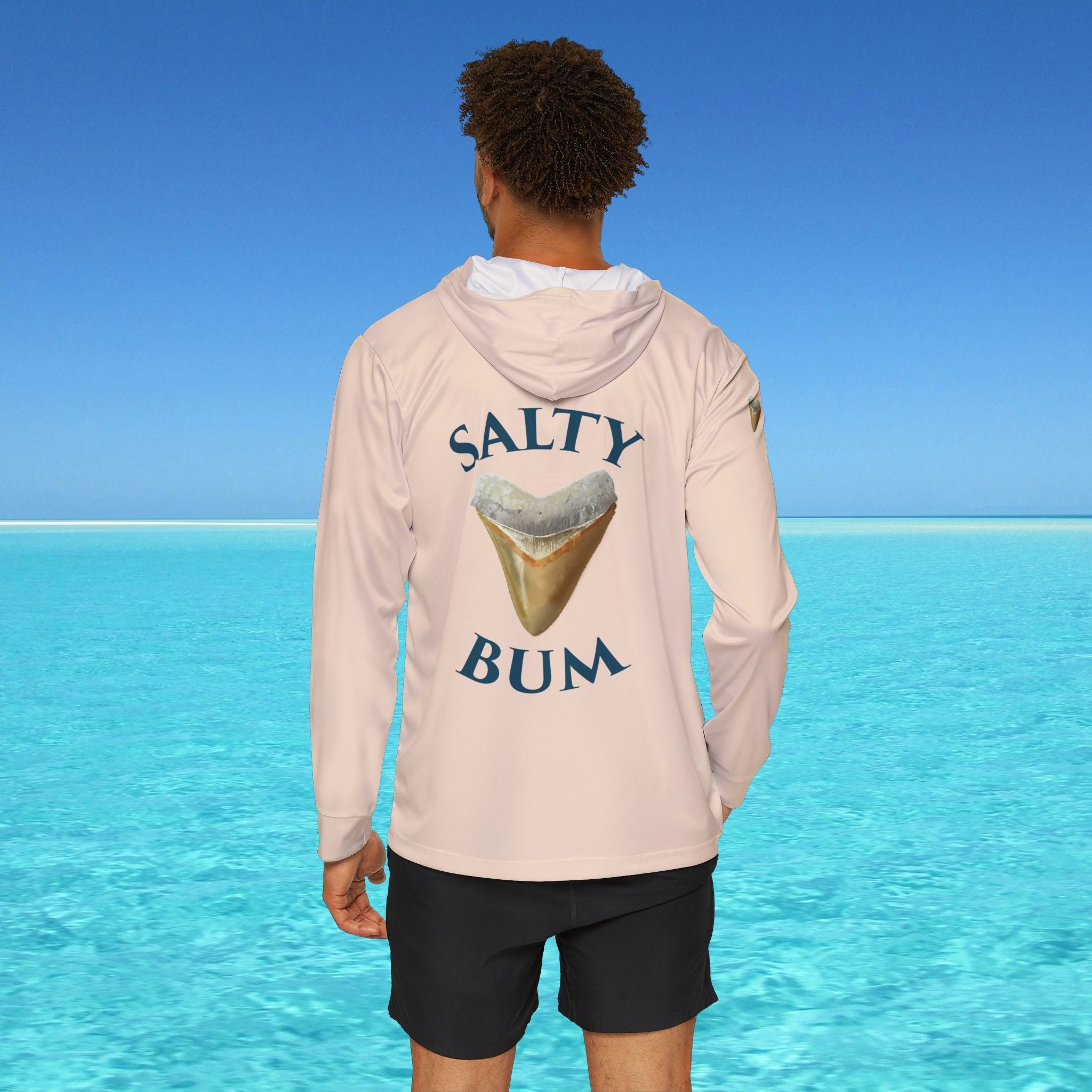 Person wearing a hoodie with 'Salty Bum' text and graphic in front of a clear blue ocean.