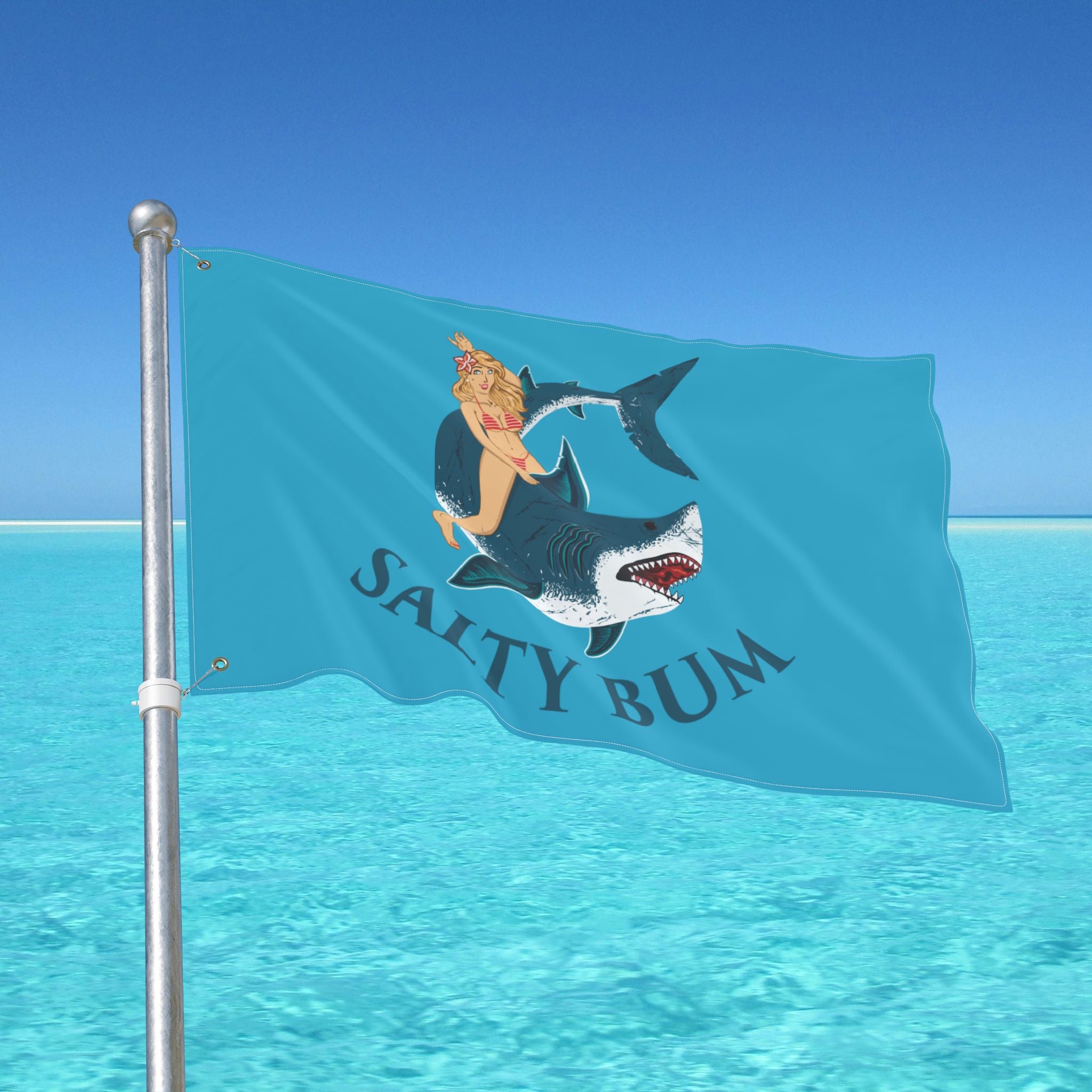 Flag with a shark and mermaid design against a clear blue sky.