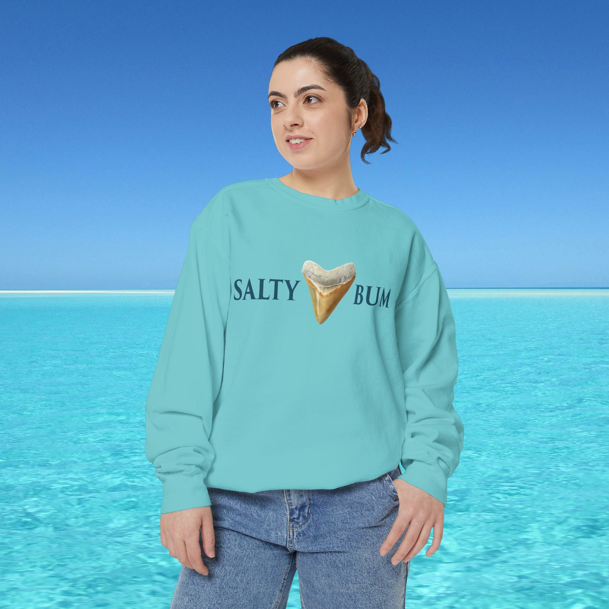 Person wearing a light blue sweatshirt with 'Salty Bum' text and ice cream graphic against a blue ocean background