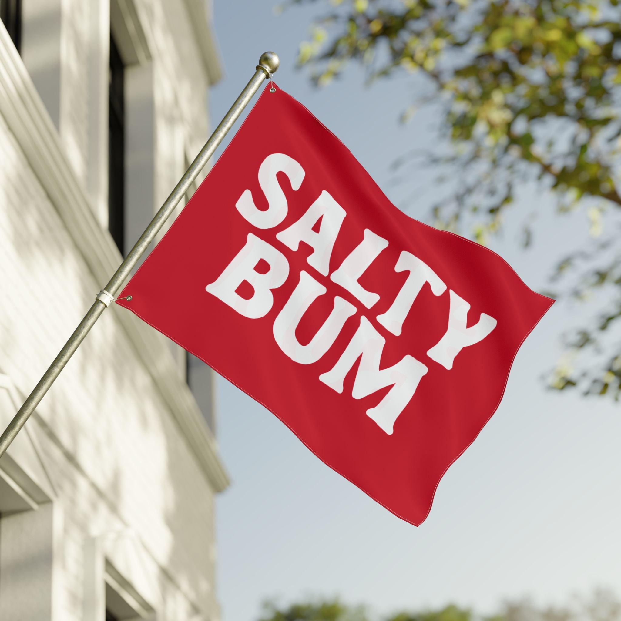 Red flag with 'Salty Bum' text waving in front of a building and trees.