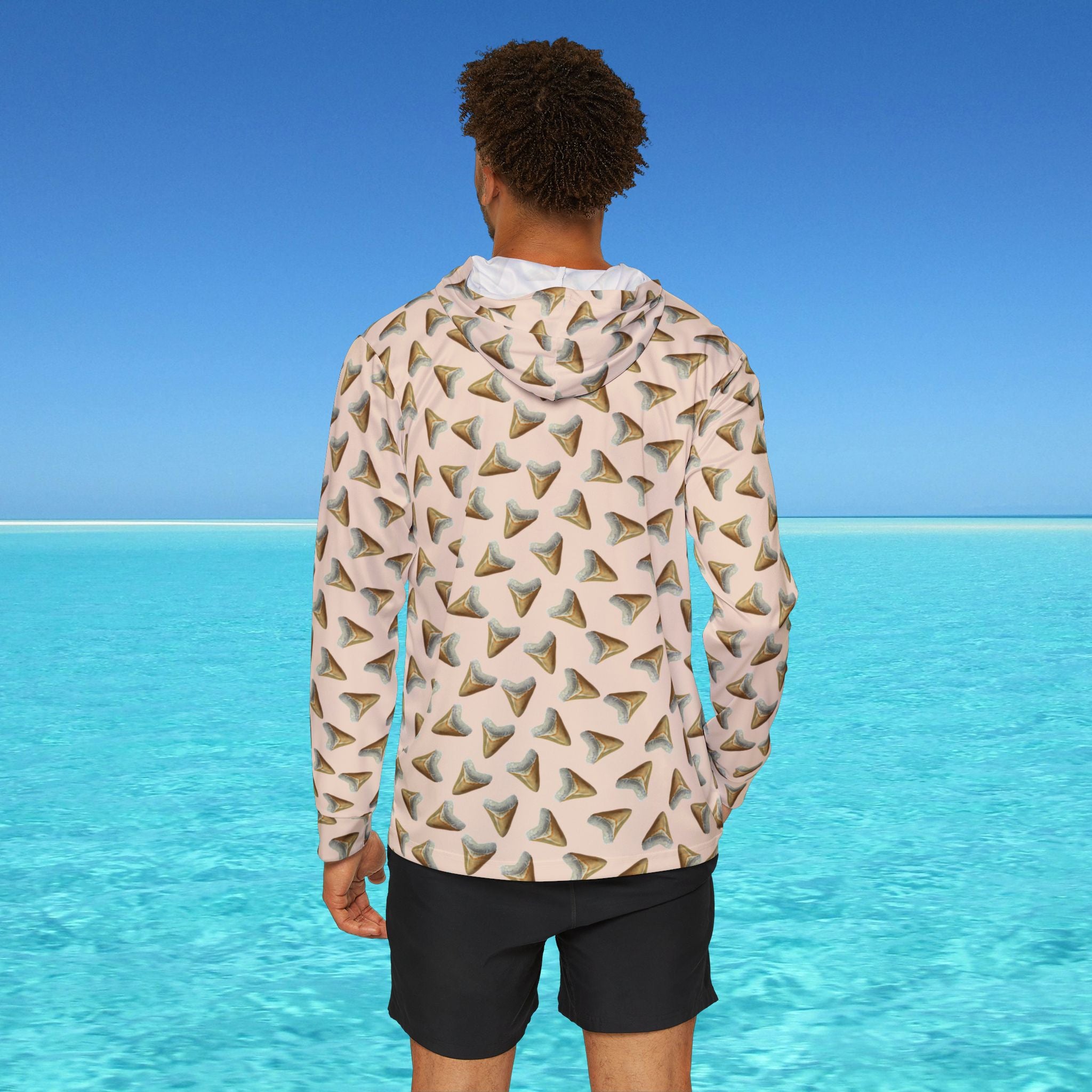 Person wearing a patterned hoodie with a blue sky and ocean background