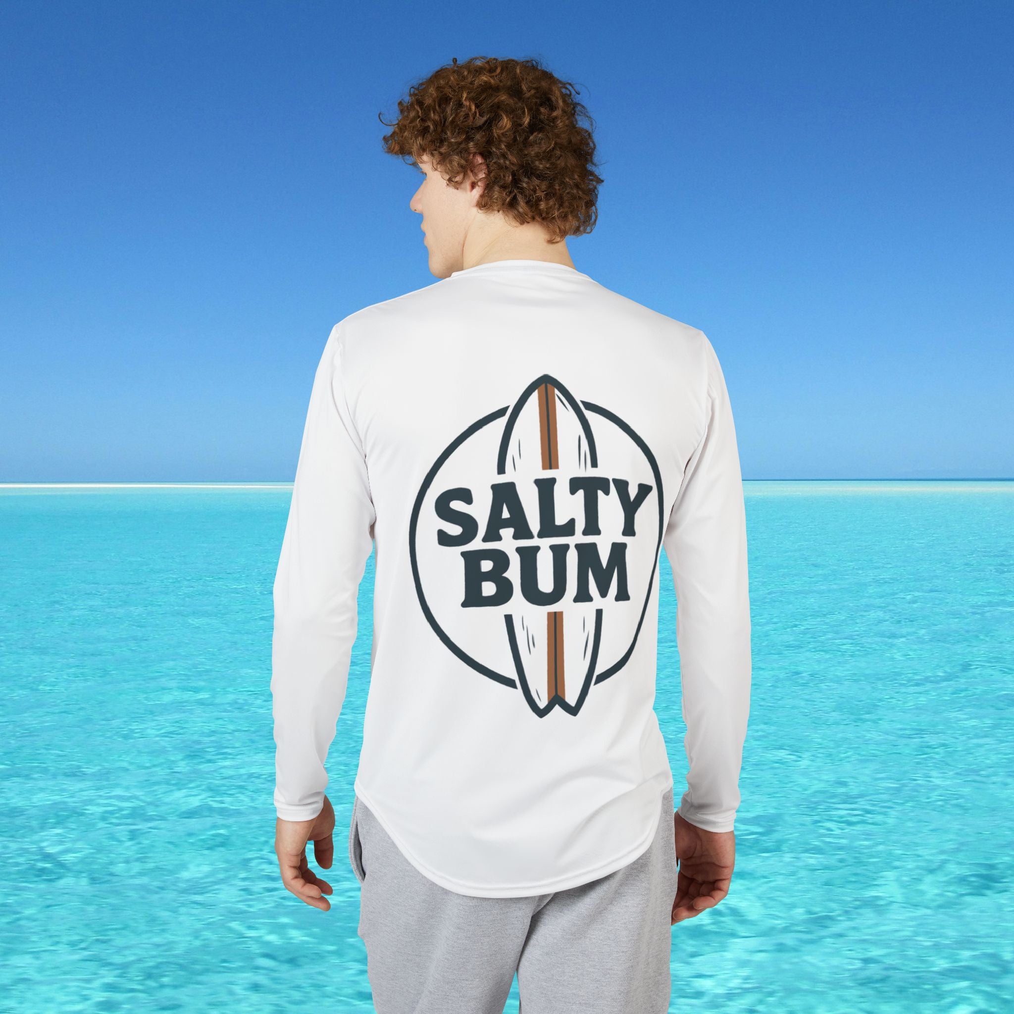 Person wearing a white long-sleeve shirt with 'Salty Bum' logo in a beach setting