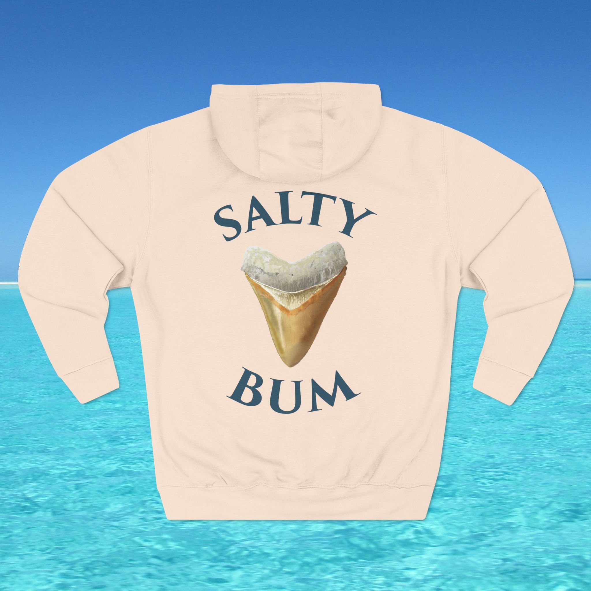 Beige hoodie with 'Salty Bum' text and shark tooth graphic on a blue water background