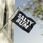 Black flag with 'Salty Bum' text waving on a pole against a blurred background