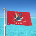 Red flag with 'Salty Bum' design featuring a mermaid and shark against a clear blue sky.