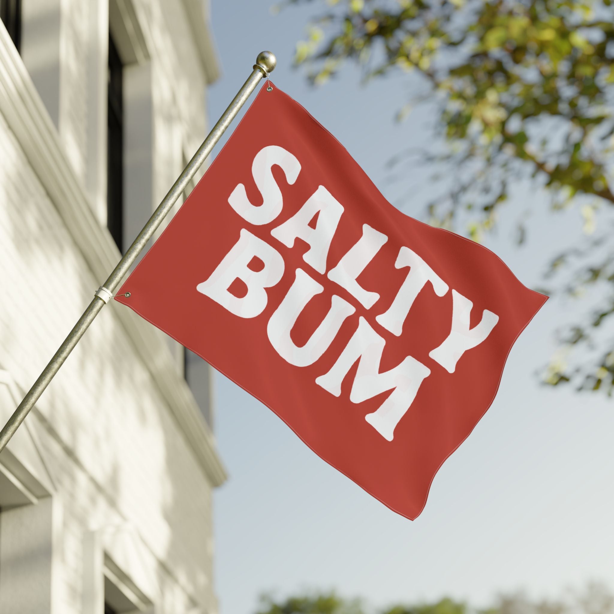 Red flag with 'Salty Bum' text on a building with trees in the background