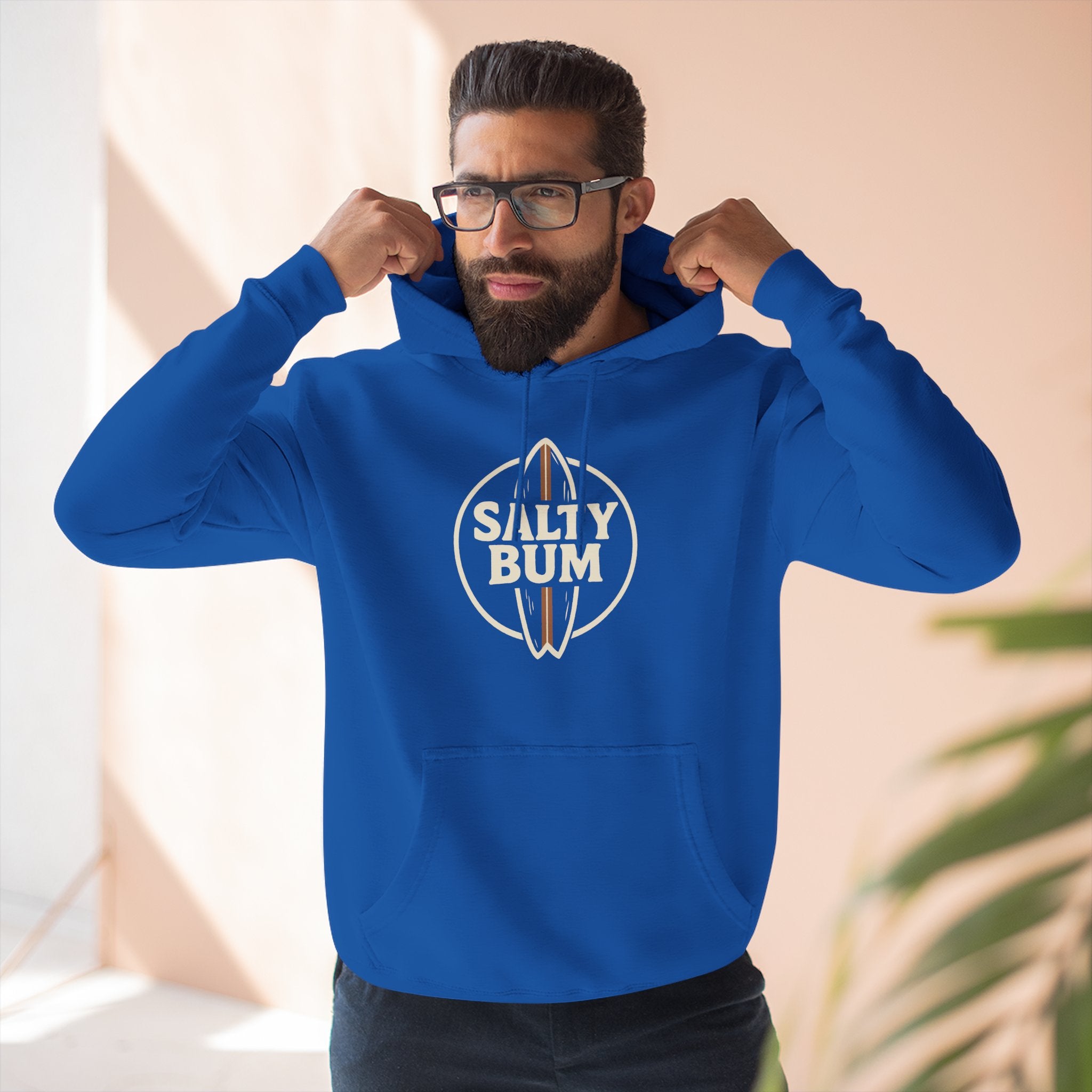 Man wearing a blue hoodie with 'Salty Bum' logo indoors