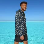 Man wearing a patterned shirt and black shorts standing in front of clear blue water and sky.