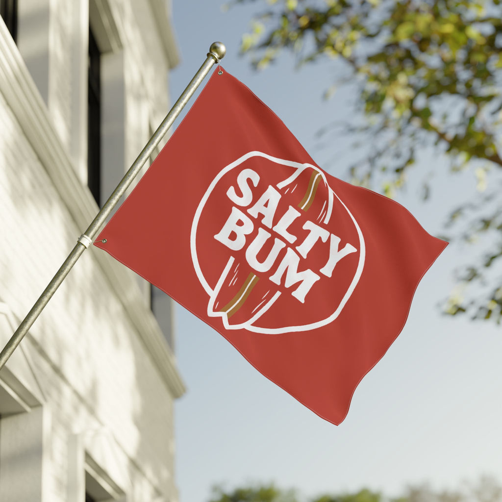 Red flag with 'Salty Bum' logo waving in front of a building