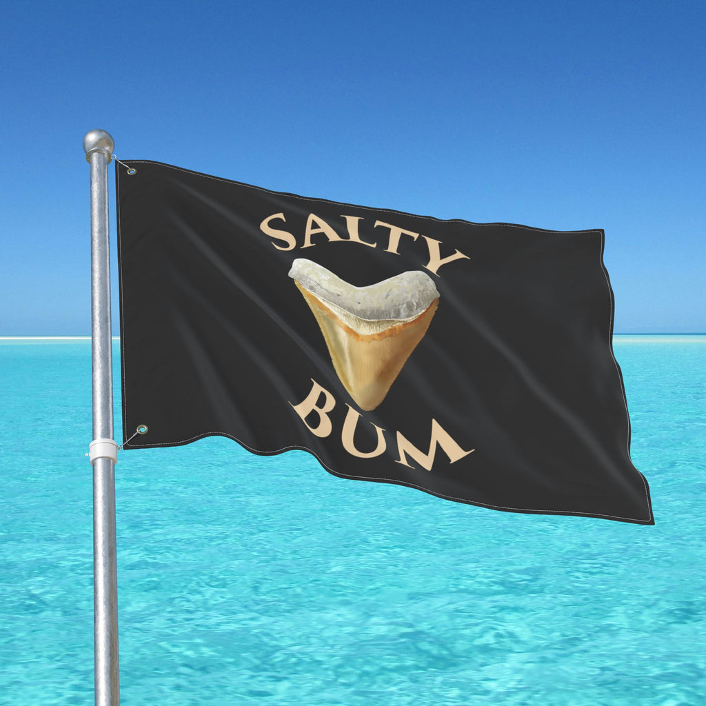 Flag with 'Salty Bum' text and a shark tooth graphic against a blue sky and ocean background.