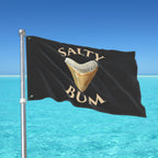 Flag with 'Salty Bum' text and a shark tooth graphic against a blue sky and ocean background.