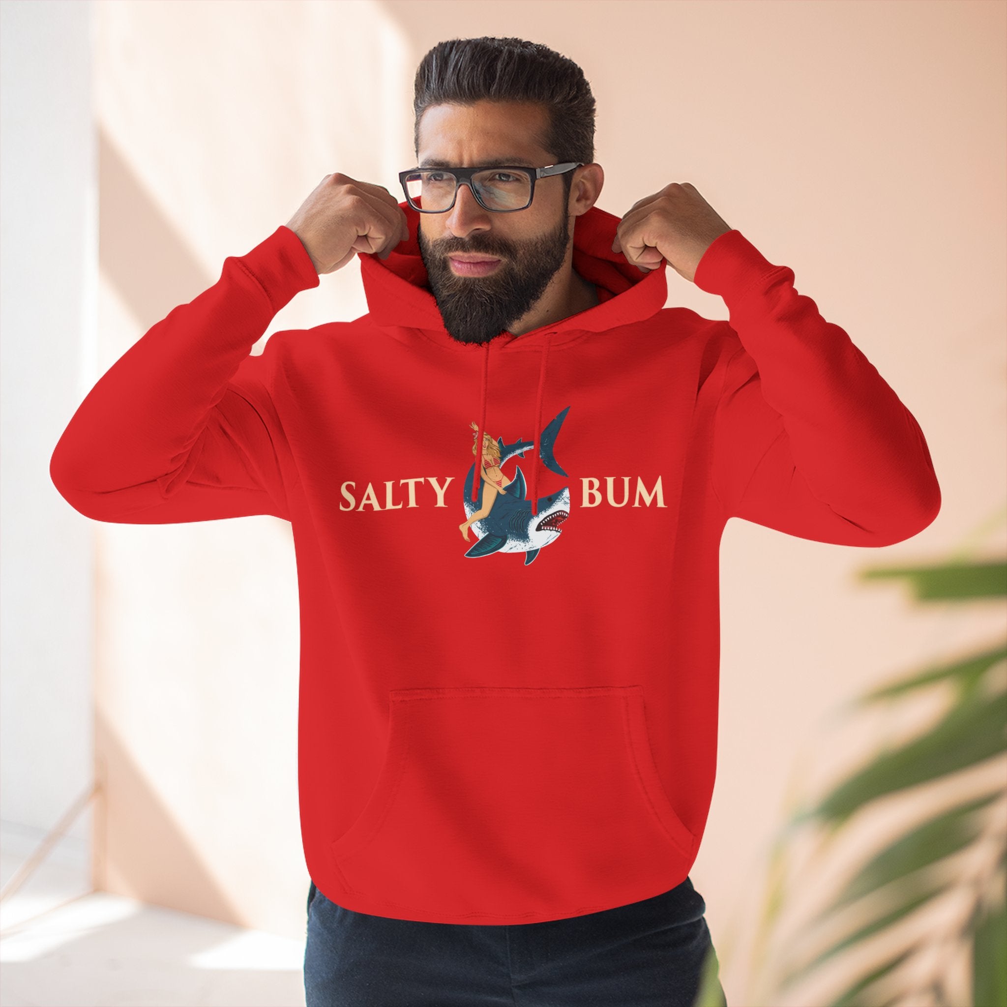 Man wearing a red hoodie with 'Salty Bum' logo, standing indoors.