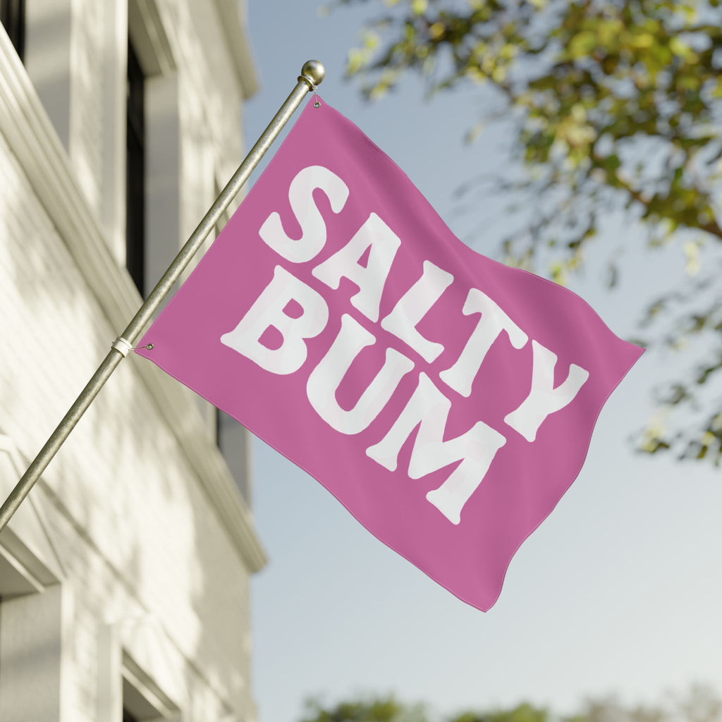 Pink flag with 'Salty Bum' text on a building facade