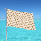 Flag with shark tooth pattern waving in the wind against a clear blue sky and ocean.