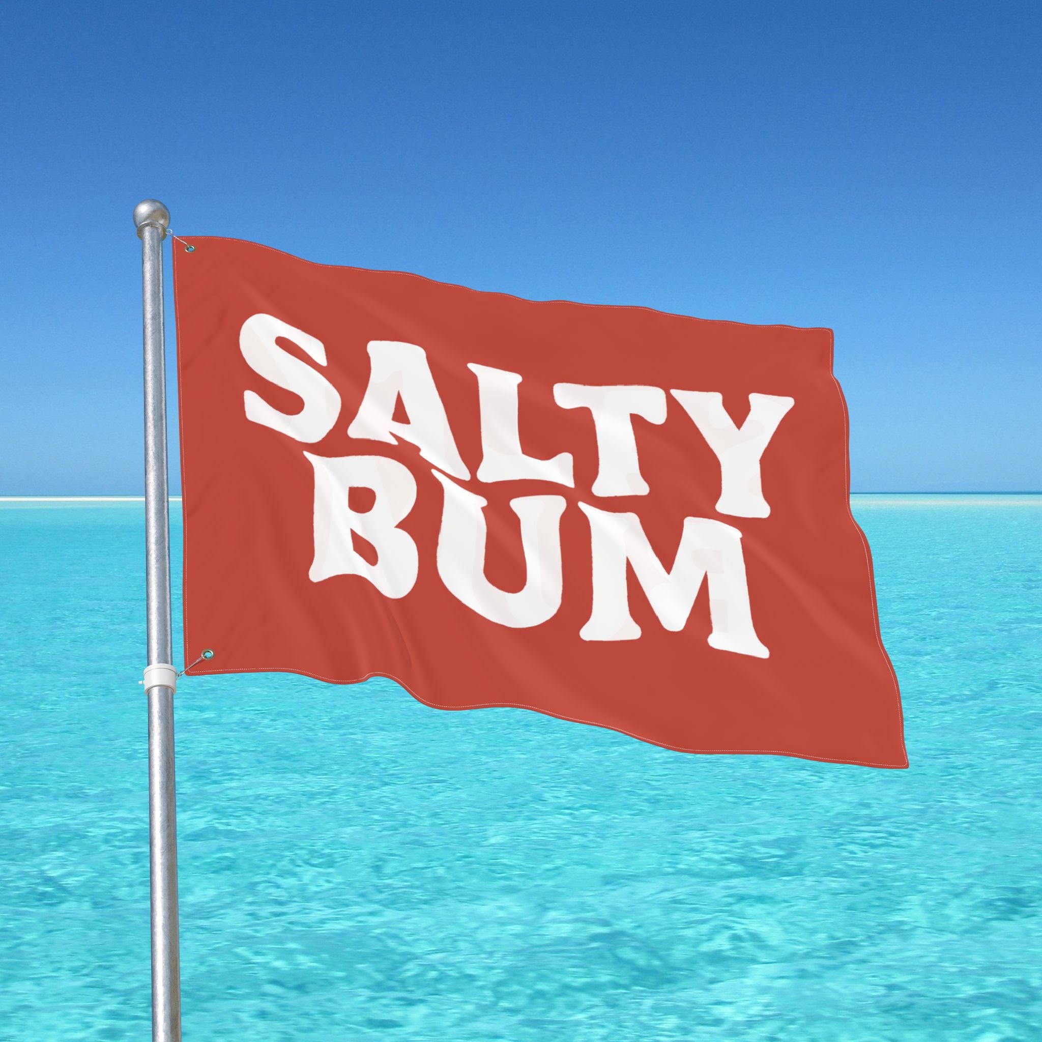 Red flag with 'Salty Bum' text against a clear blue sky and ocean.