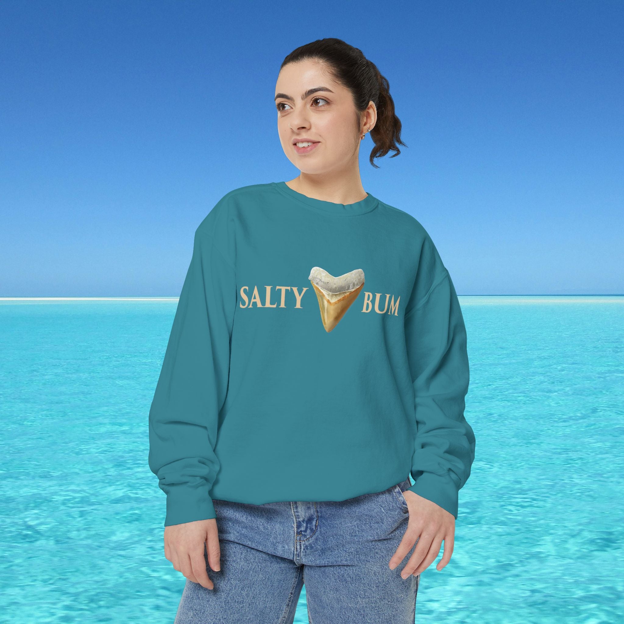 Person wearing a teal sweatshirt with 'Salty Bum' text and ice cream graphic against a blue ocean background