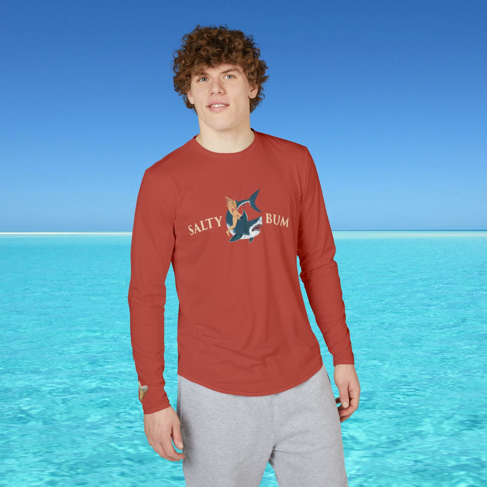 Person wearing a red long-sleeve shirt with 'Salty Bum' logo against a blue water and sky background