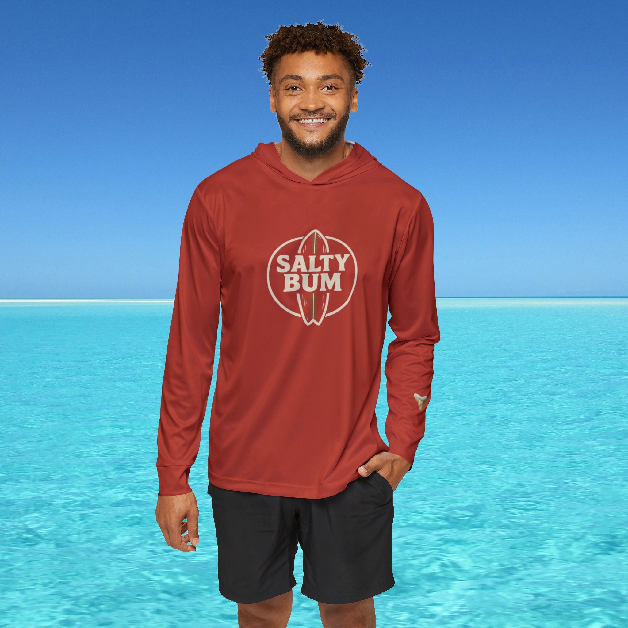 Man wearing a red 'Salty Bum' hoodie with a blue ocean background
