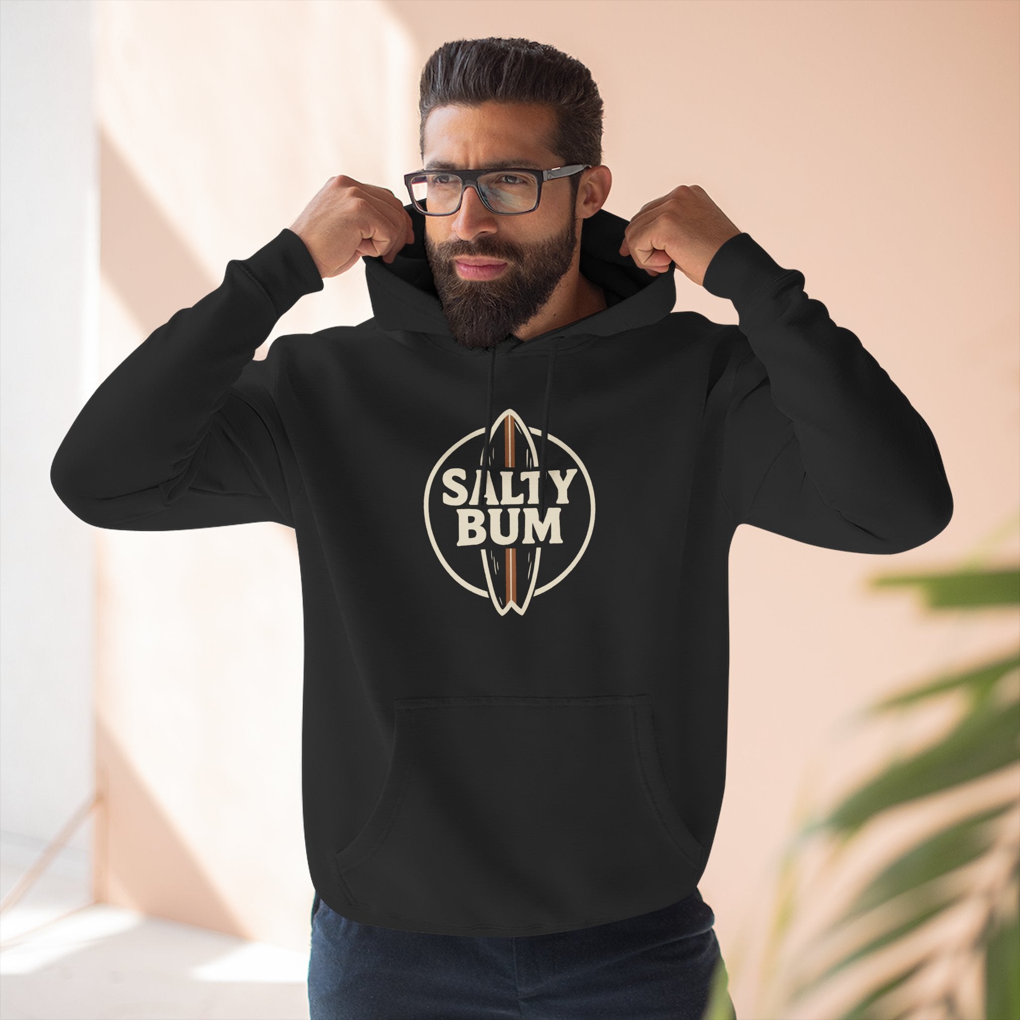 Man wearing a black hoodie with 'Salty Bum' logo indoors