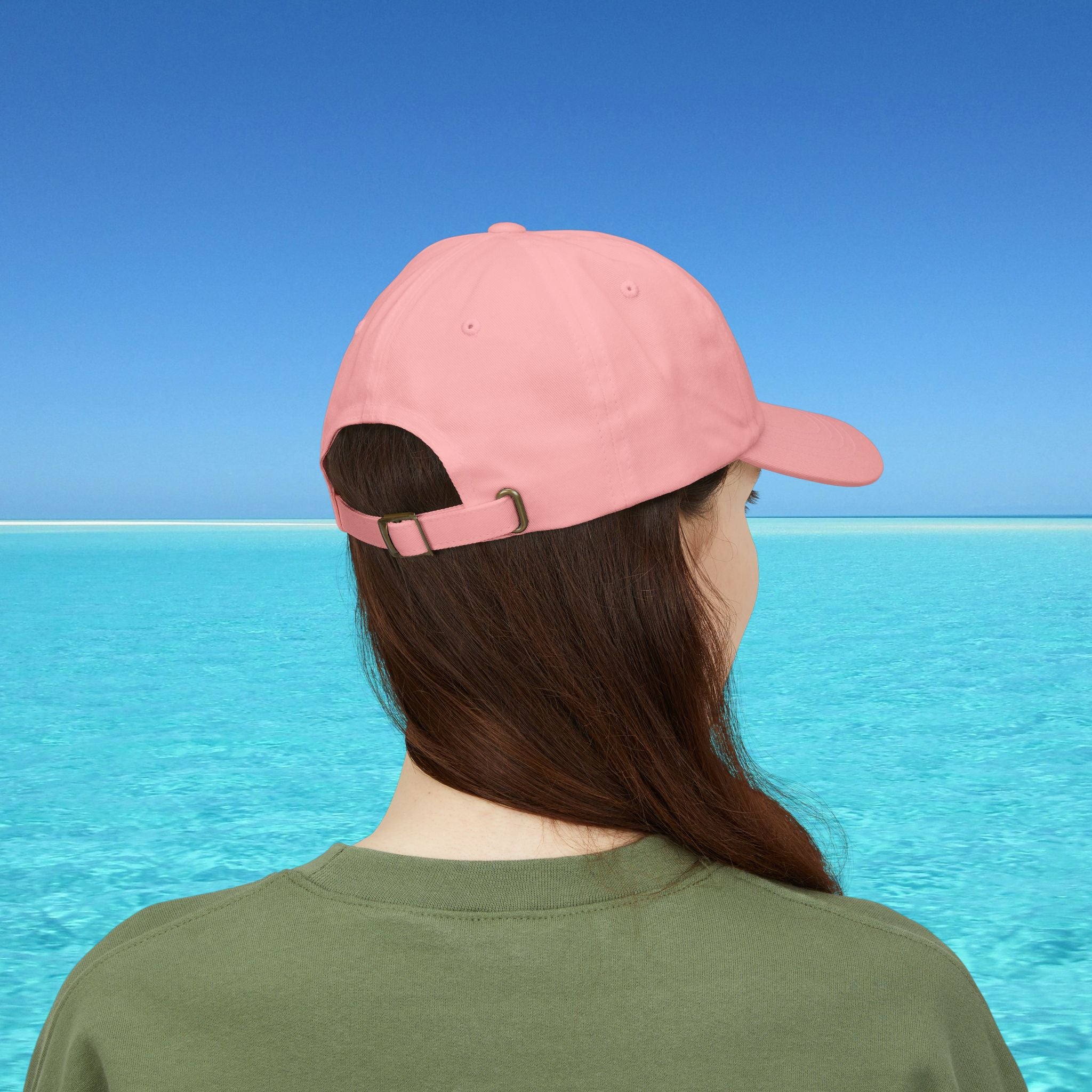 Person wearing a pink cap with a clear blue sky and water background