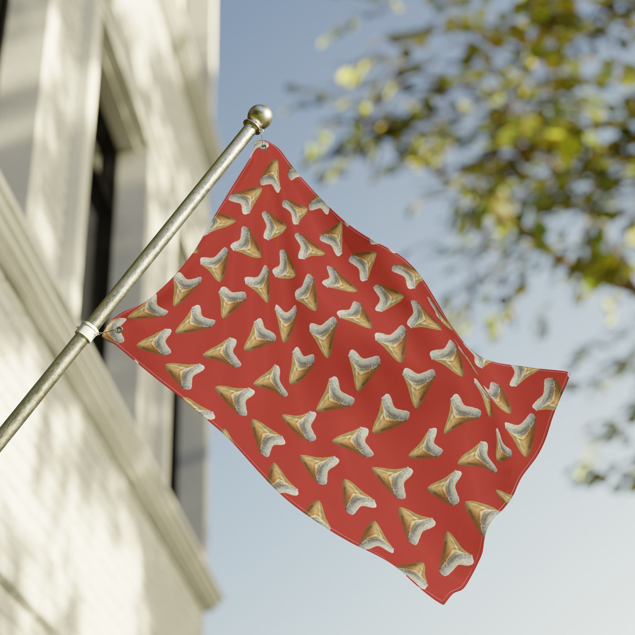 Red flag with gold and white pattern on a pole against a blurred background