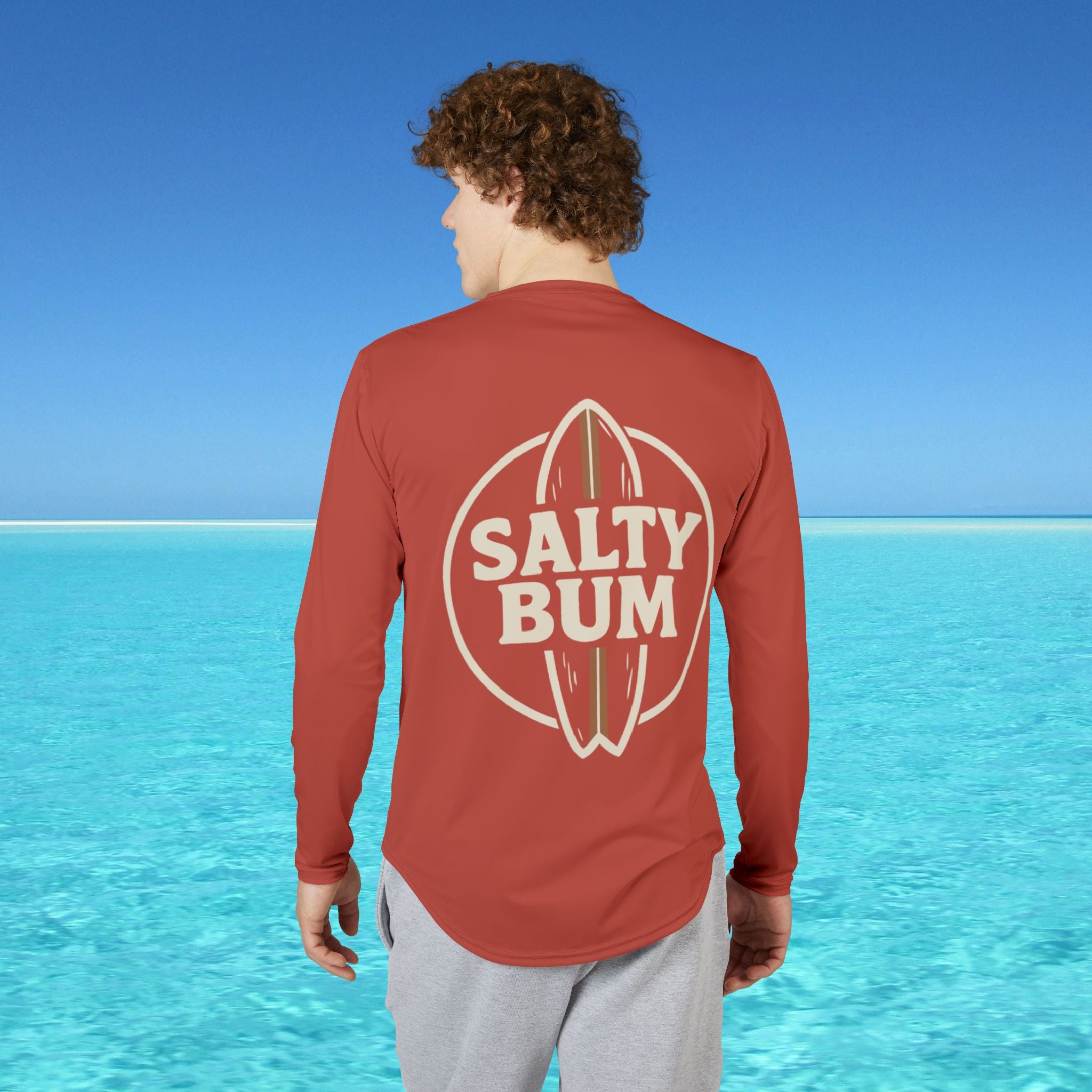 Person wearing a red 'Salty Bum' shirt with a blue ocean and sky background