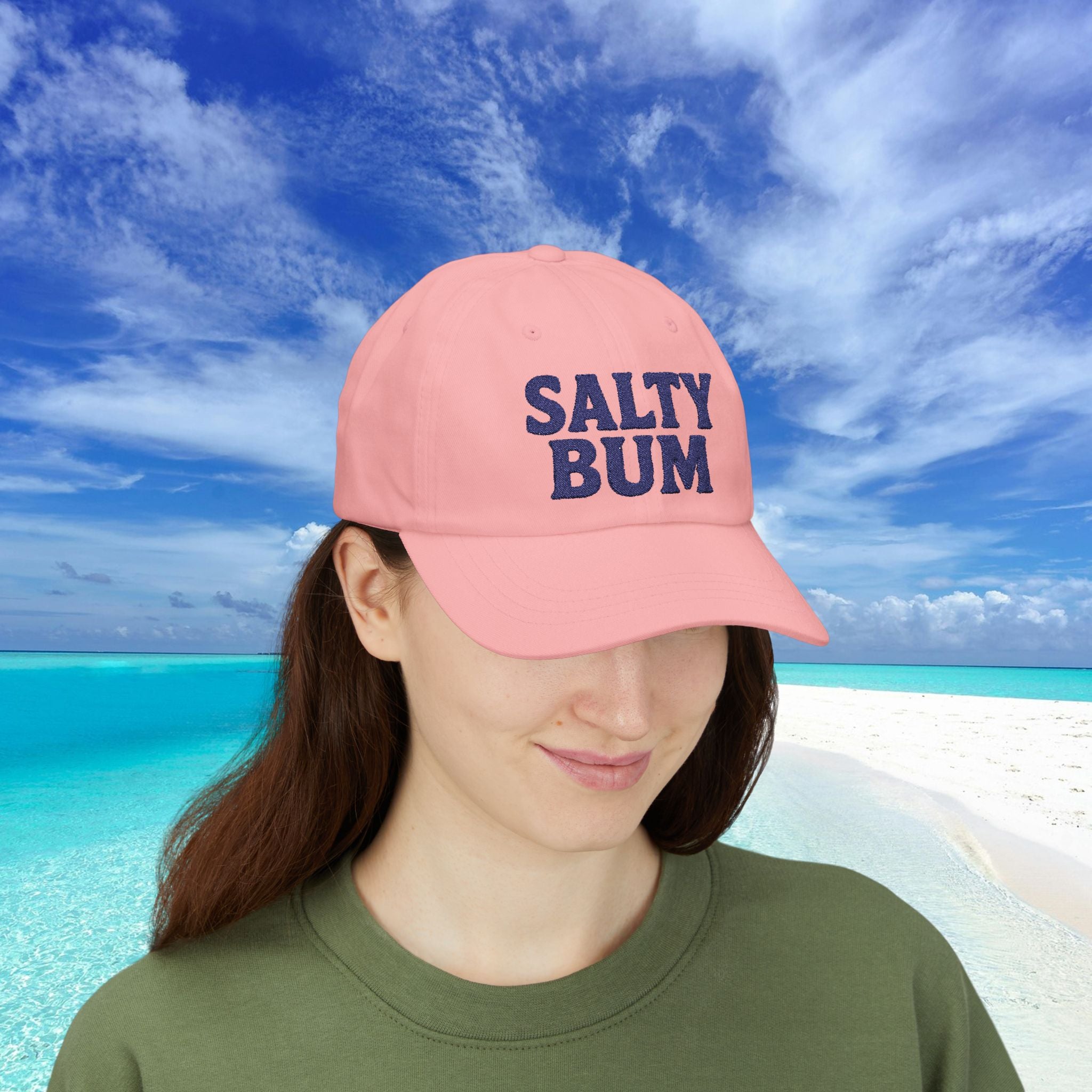Person wearing a pink cap with 'Salty Bum' text against a beach background
