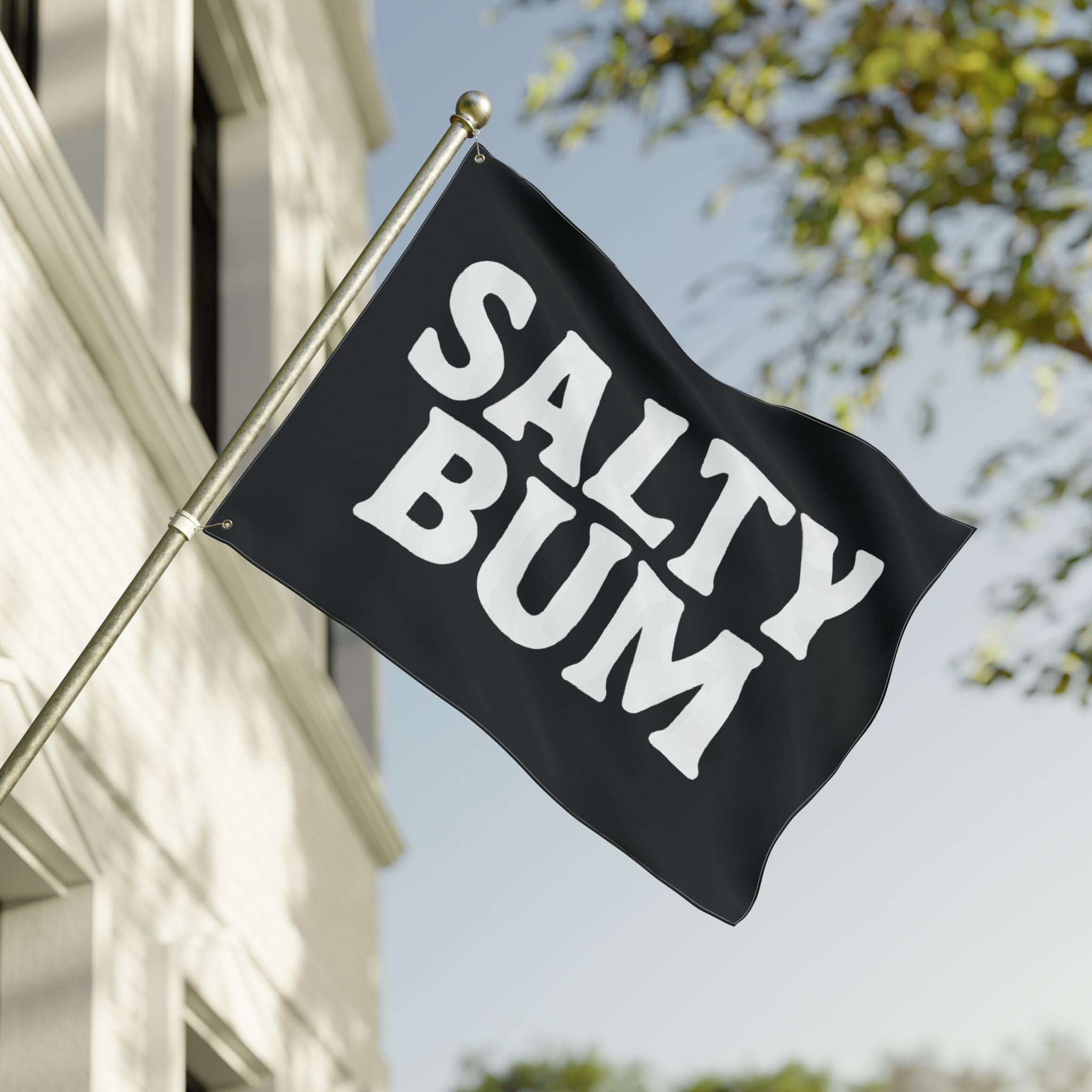 Black flag with 'Salty Bum' text waving in front of a building and tree.