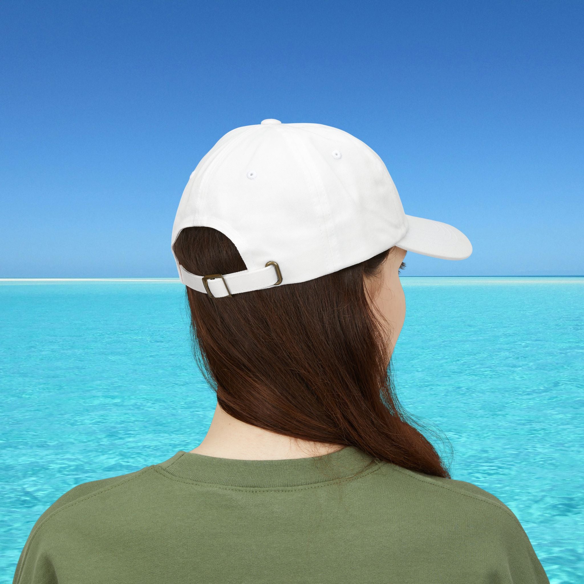Person wearing a white cap and green shirt with a clear blue sky and water background
