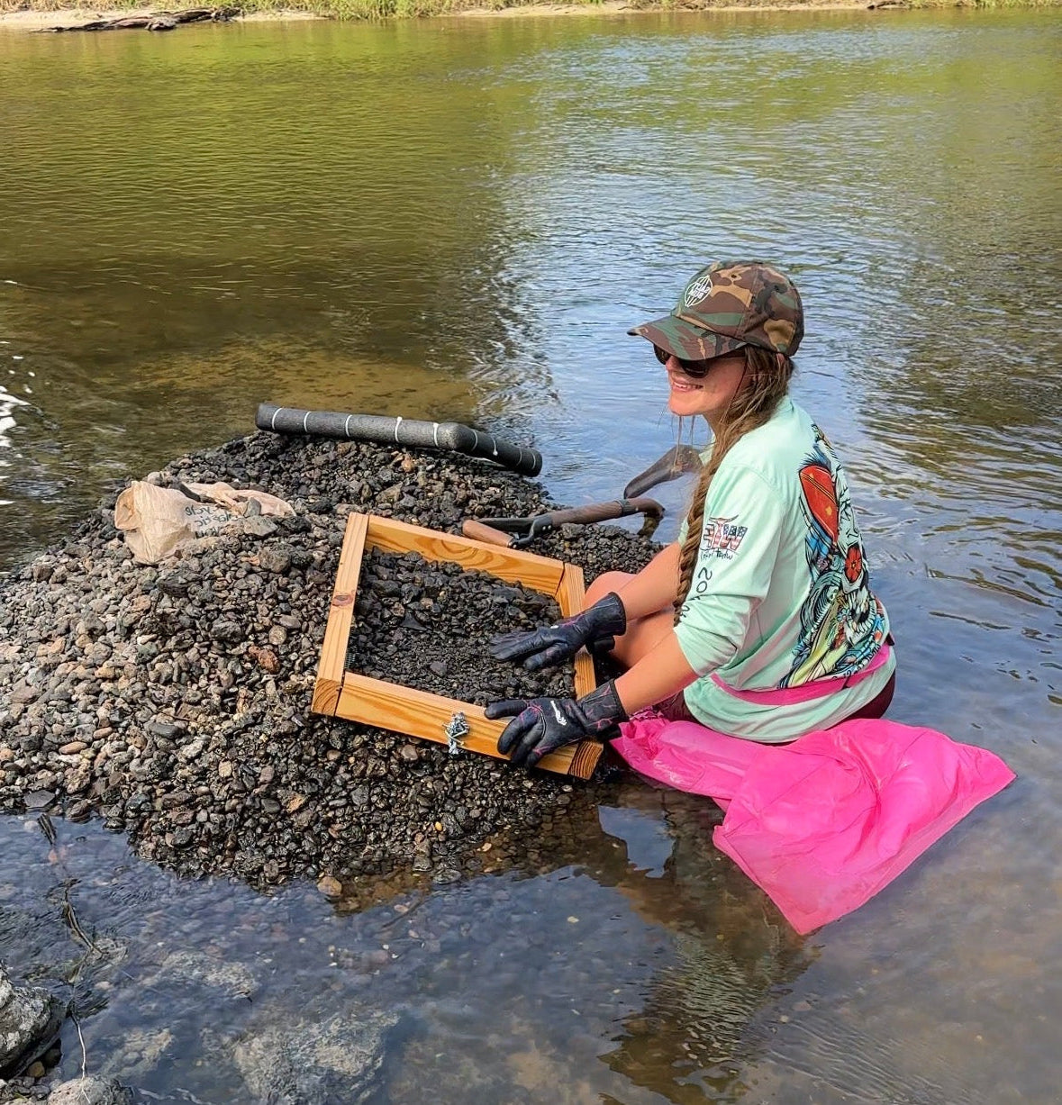 Person sitting in water with a screen and tools, likely involved in fishing or catching aquatic animals.